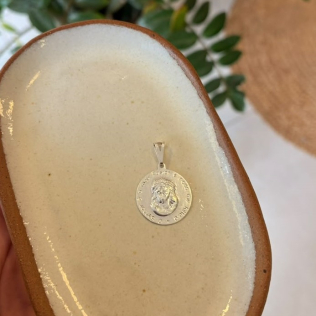 Medalha prata com relevo De Jesus e escrita.
